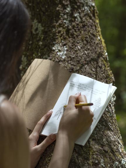 Journaling outside against a tree