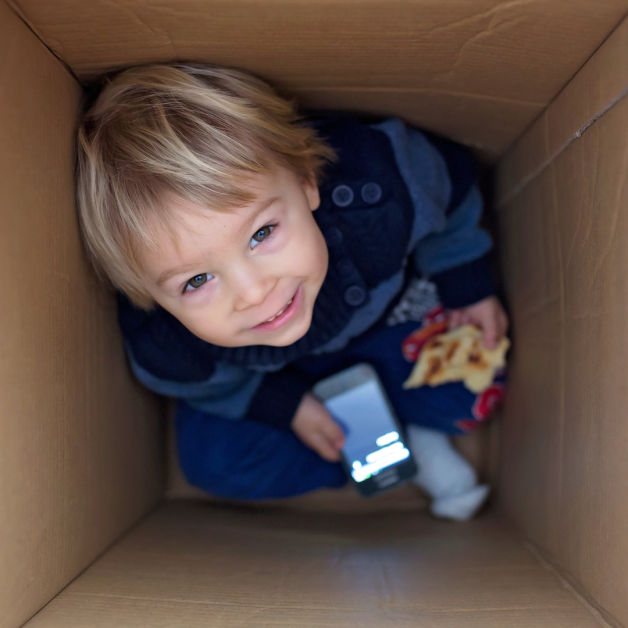 Young boy playing in a cardboard box