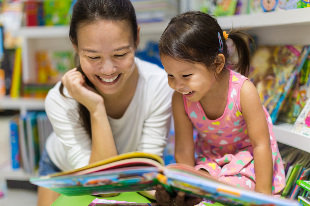 mother reading a paper book to daughter