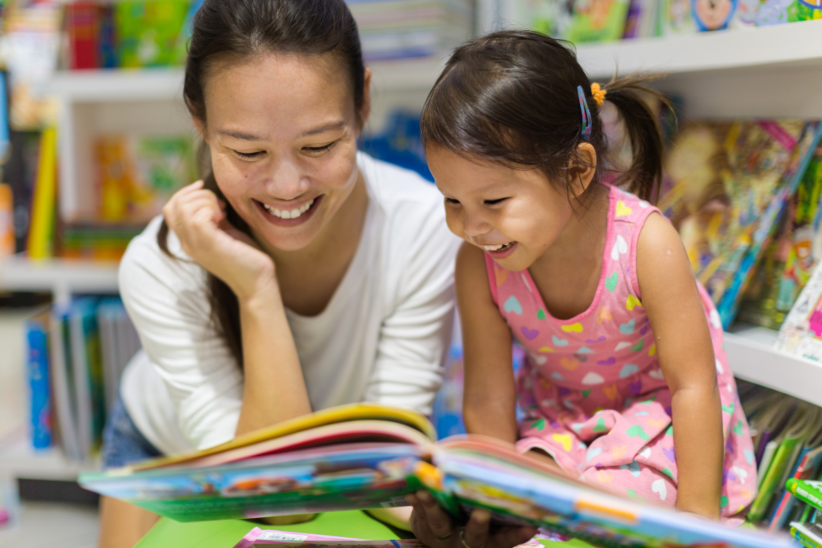 mother reading a paper book to daughter 