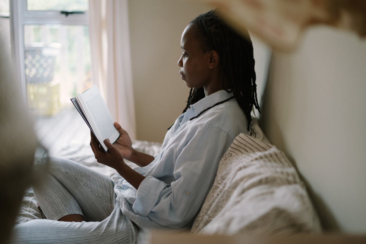 women reading a paper book in bed