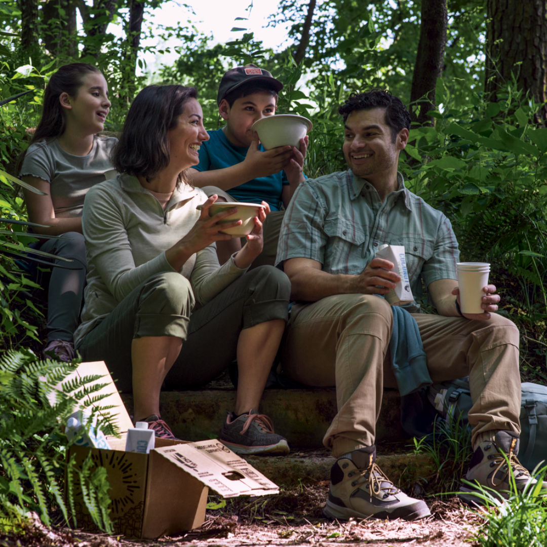 family picnicking in the woods with a paper cooler