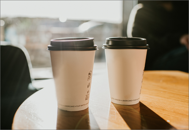 Two white paper coffee cups with plastic lids.