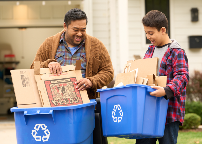 Father and son practicing proper recycling habits by emptying and flattening their boxes before putting them in the recycling bin.