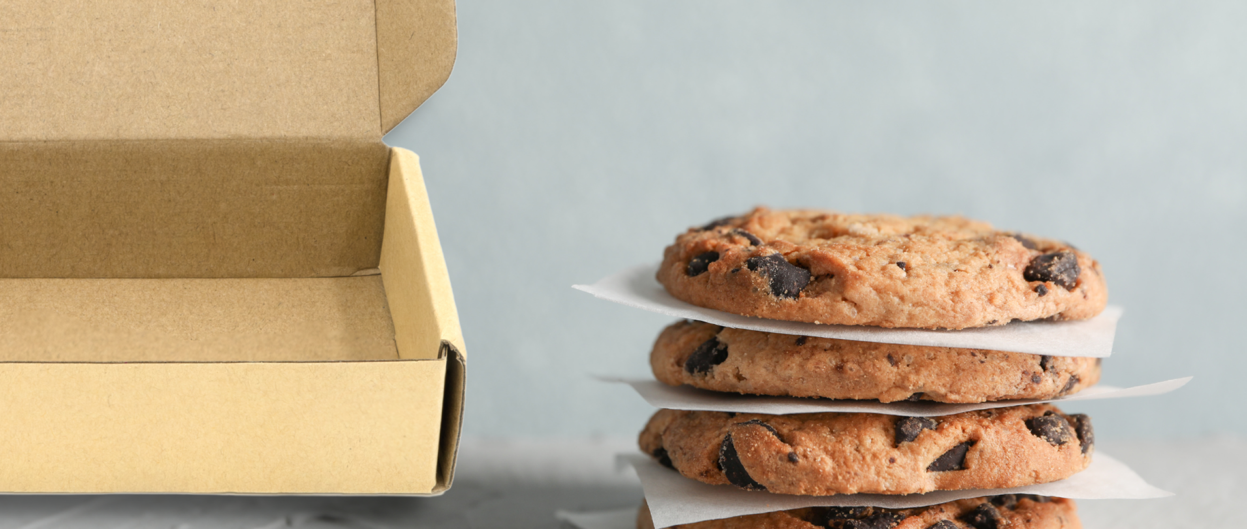 Stack of chocolate chip cookies next to a brown box