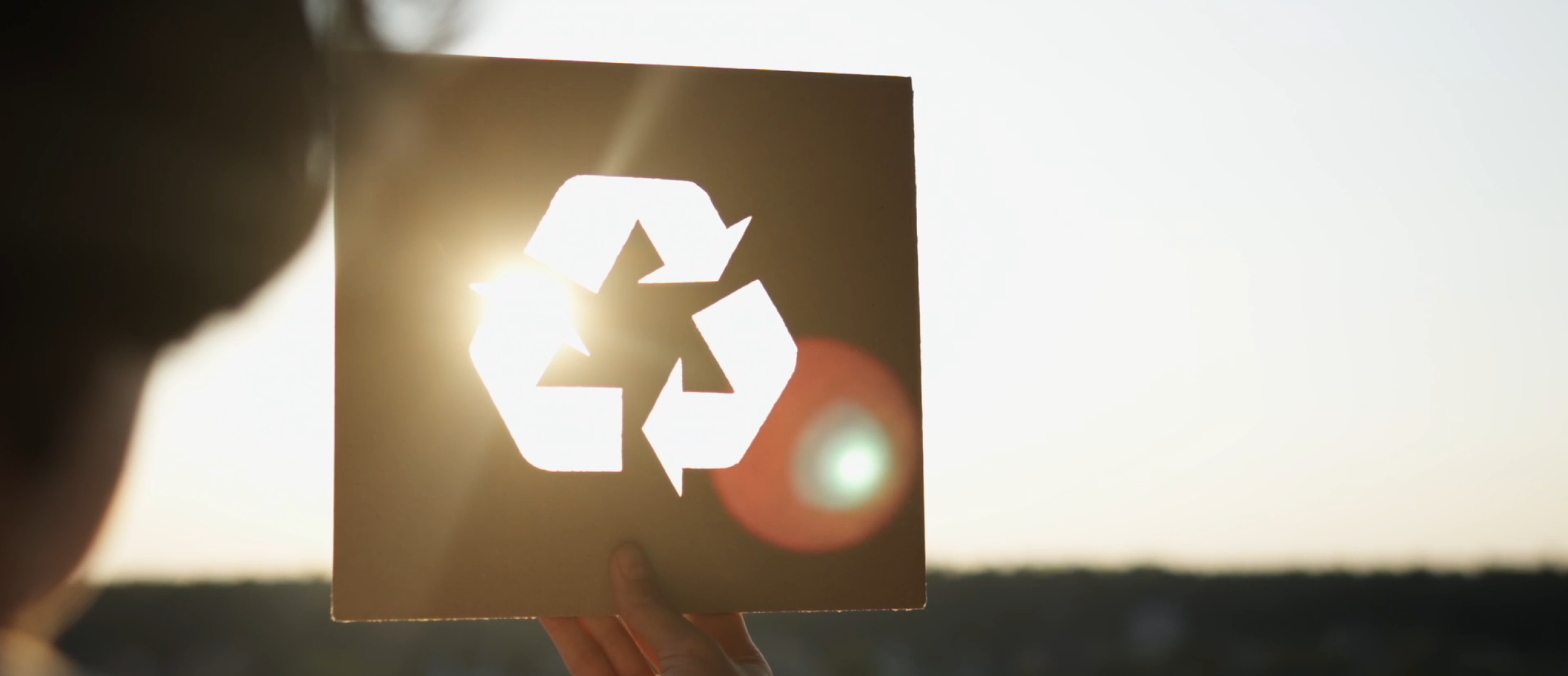 Person holding a sign with a recycling symbol