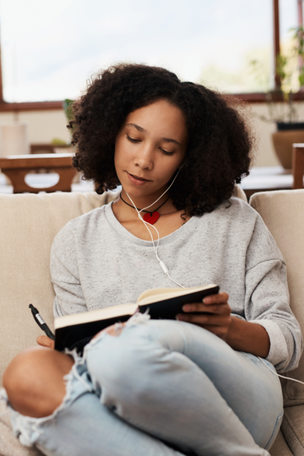 Lady journaling while listening to music on her couch