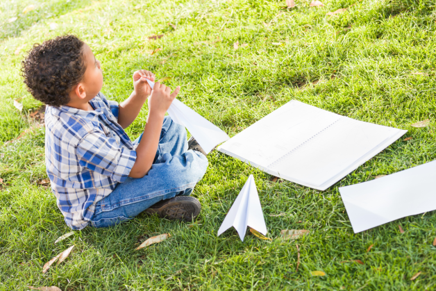 Kid making paper airplanes outside