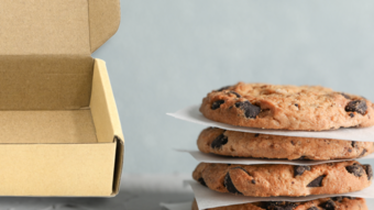 Stack of chocolate chip cookies next to a brown box