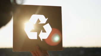 Person holding a sign with a recycling symbol