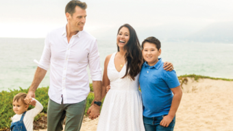 Family of 4 holding hands walking on the beach