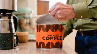 Man opening a paper can of coffee beans.