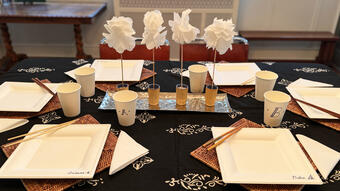A dinning table set with paper plates, napkins and cups