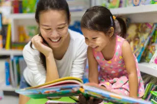 mother reading a paper book to daughter