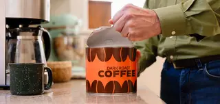 Man opening a paper can of coffee beans.