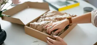 Woman packaging an ecommerce order in a cardboard box