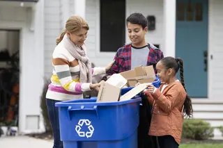 Parent and kids recycling outside the house