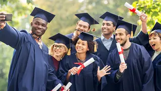 Graduates holding diplomas take selfie